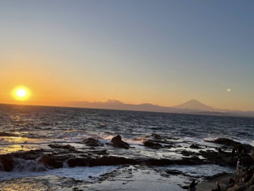 江の島イルミネーションが始まる前の夕暮れ時に、岩屋周辺の海から見える美しい夕日と富士山のシルエット